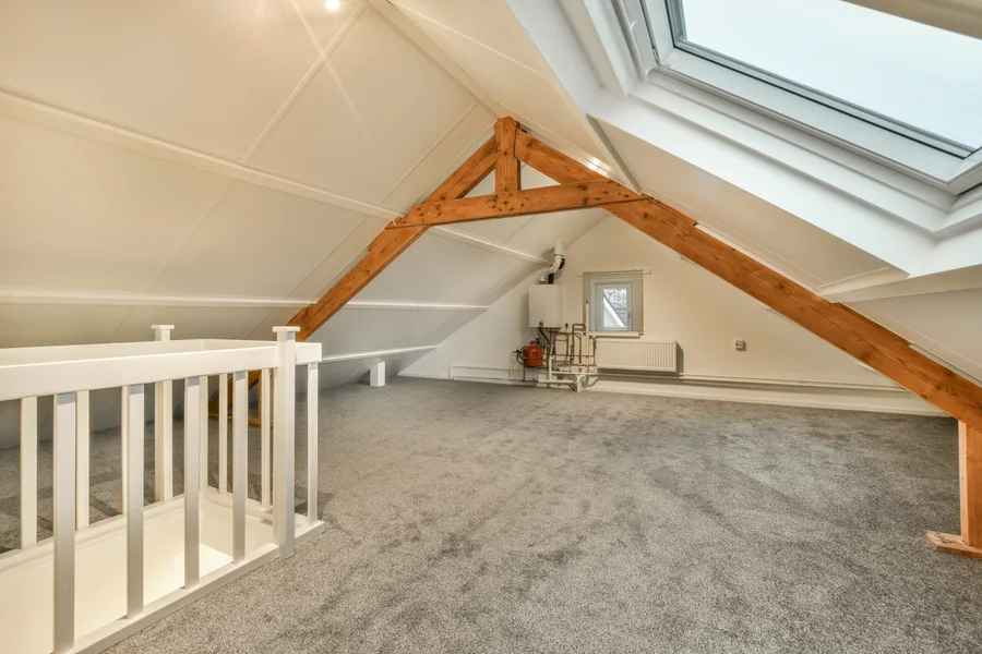 Loft conversion with exposed roof trusses and roof windows either side