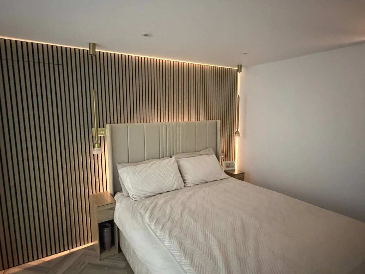 Finished master loft bedroom with a wood-slat feature wall and fitted lighting, built by Loft Life in London and Kent