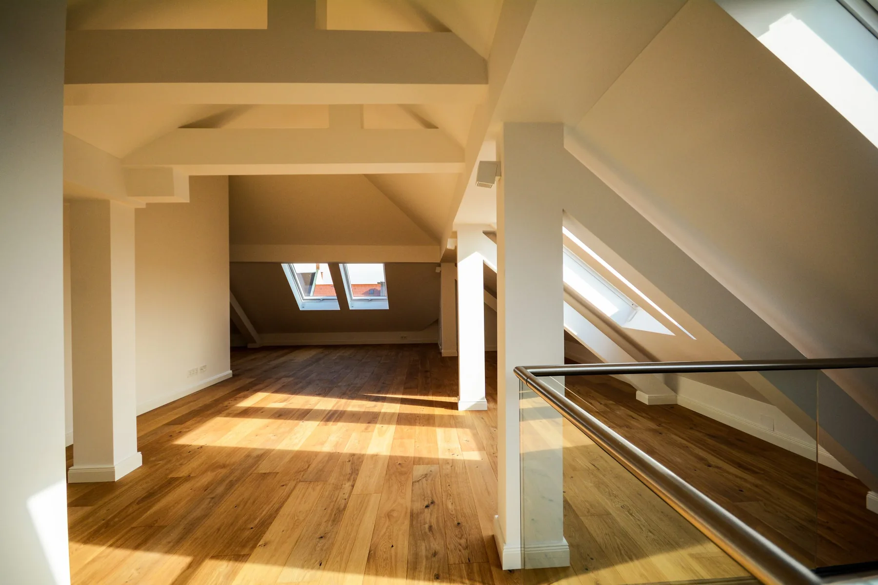Loft conversion bedroom space with roof windows bringing in natural light over a wood floor
