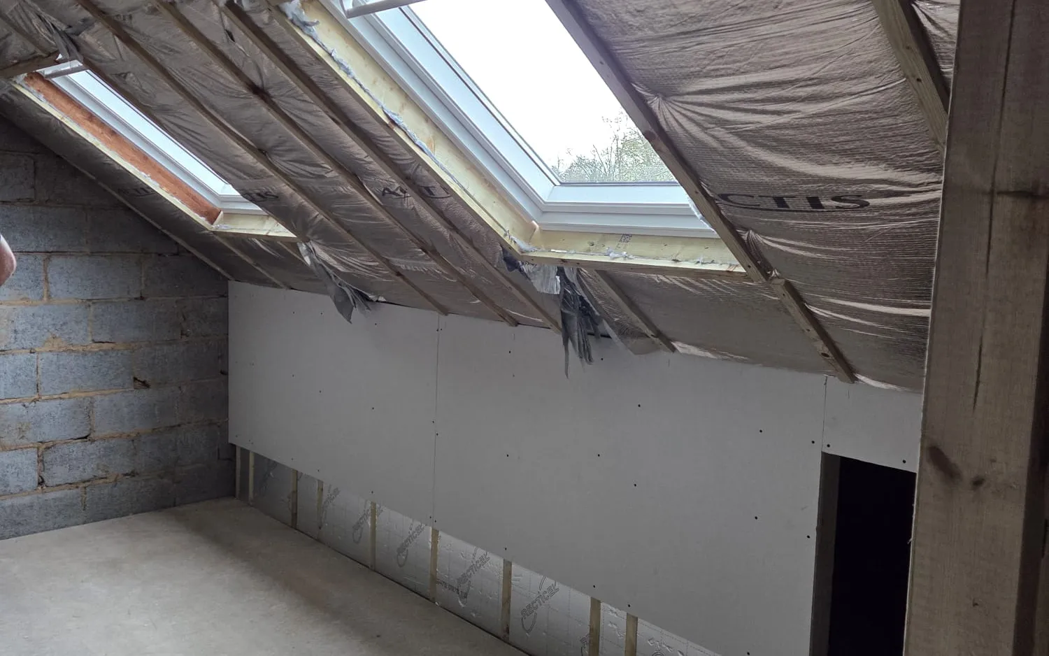 Rear box dormer loft conversion in Penge, the new bedroom with roof windows and a sloped ceiling during the build