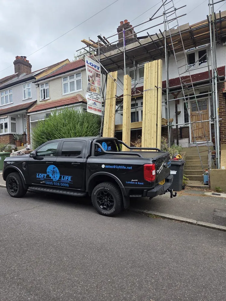 The branded Loft Life van parked outside a house being converted, with scaffolding up