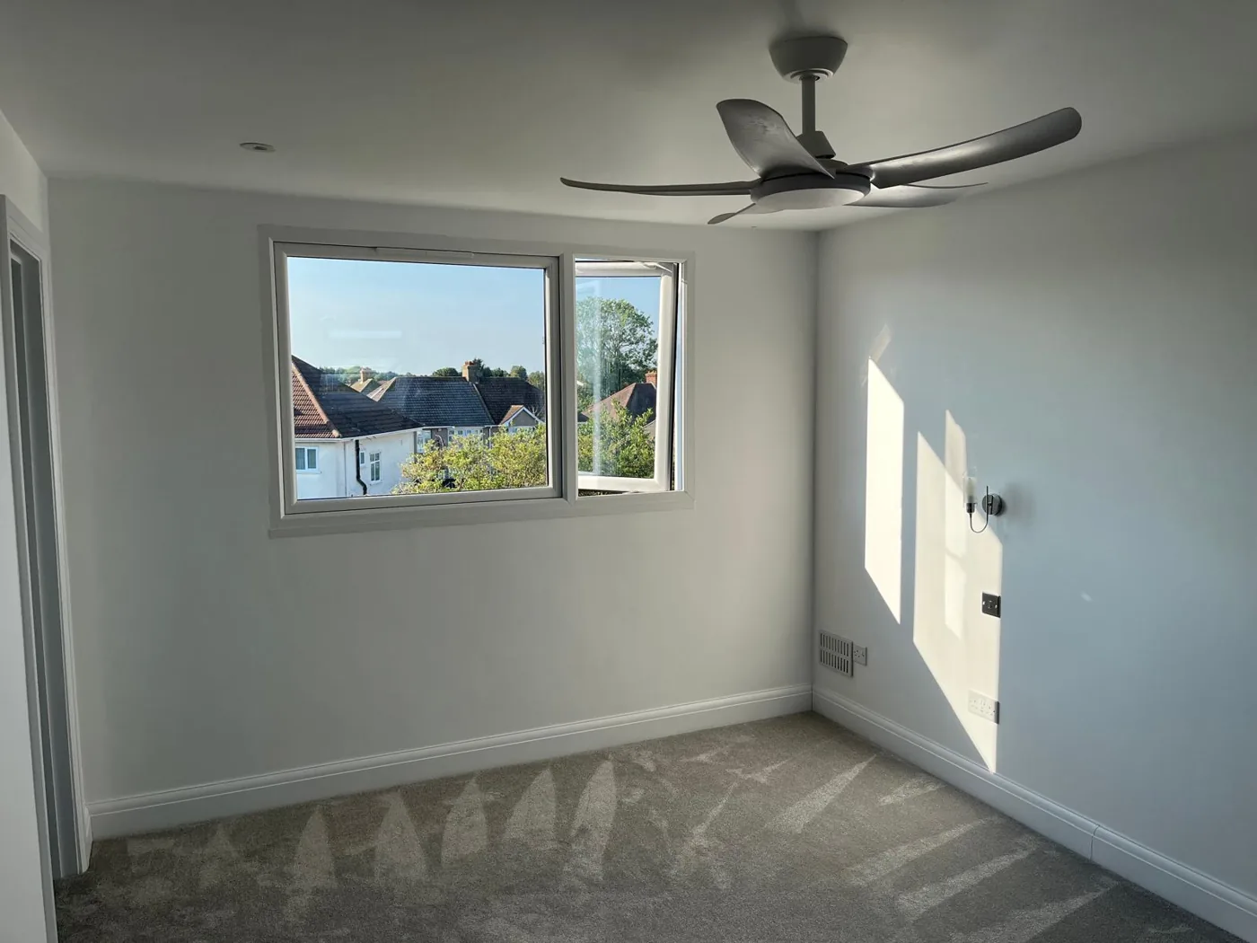 Bright finished loft room with a window and ceiling fan